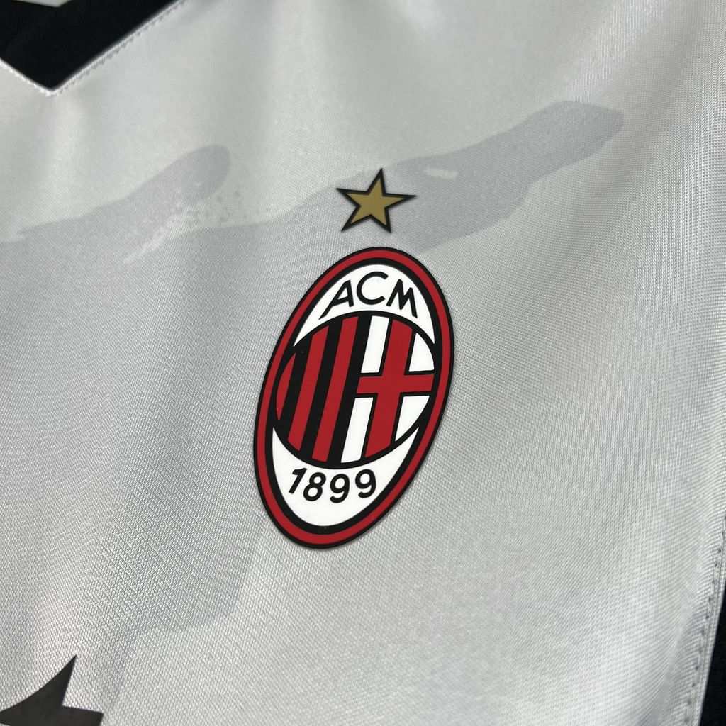 Detail znaku AC Milan s hviezdou a jemnej sivej grafiky na bielom drese
