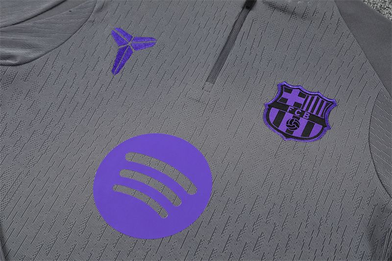 Detail fialového klubového znaku, symbolu Kobe Bryant a jemného vzoru na sivom vrchnom diele