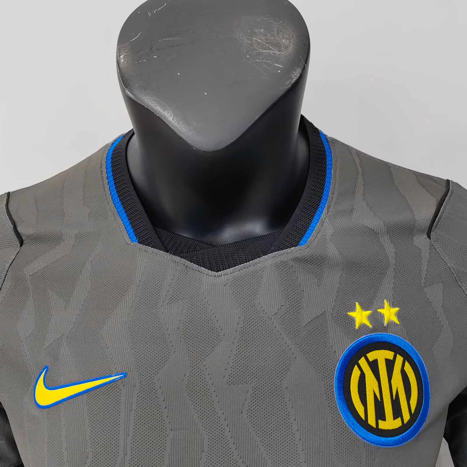 Detail čierneho hrudného pásu a modrého lemovania na sivom drese Inter Milan 2026/27
